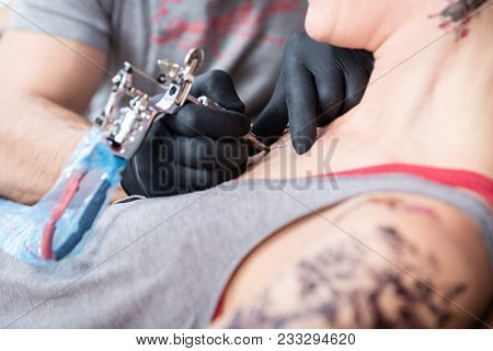 Side view close-up of a trendy woman smiling while getting a painless new tattoo in the modern studio of a skilled artist 