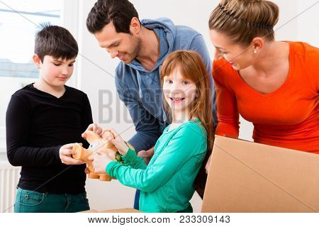 Family moving into new home carrying packing cases