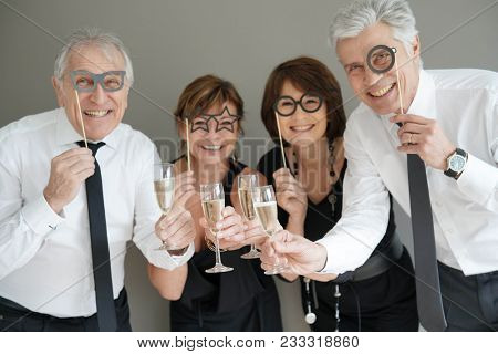 Senior people celebrating with party photobooth props