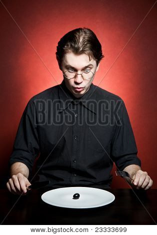 Funny and strange young man eating grape