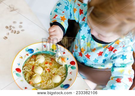 Adorable Baby Girl Eating From Spoon Vegetable Noodle Soup. Food, Child, Feeding And Development Con