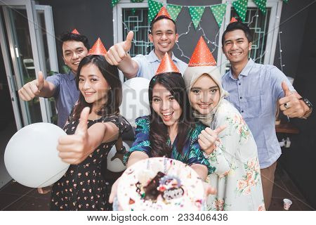 Portrait Of Happy Young Asian People Celebrating Birthday Of Their Friends Together At Home And Show