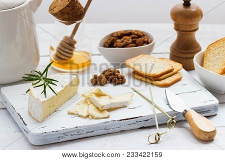 Cheese Plate Served With Crackers, Honey And Nuts. Camembert On White Wood Serving Board Over White 