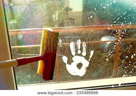 Hand Print On Dirty Window And Squeegee Cleaning The Glass. Cleaning Windows With A Squeegee.