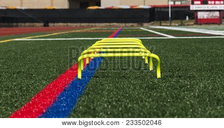 Six Inch Yellow Banana Hurdles Set Up One In Front Of The Other On A Green Turf Field At Track And S
