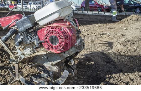 Walking Tractor Equiped With Plow At Urban Park Close To Working Gardener. Soil Preparation Concept