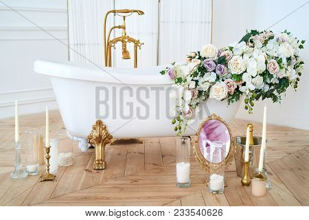 Beautiful Luxury Vintage Empty Bathtub With Lush Floral Decorations And Candles, Mirror On The Floor
