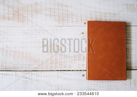 Red Book And Hourglasses Lie On A Wooden Table. Top View. Layflat