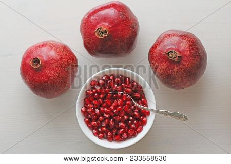 Grains Of Red Ripe Pomegranate Lie In A White Bowl With A Spoon. Big Ripe Red Granets Or Garnets. Fr