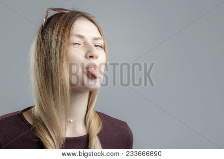 Beautiful Girl Thumbs Up, Tongue Out And Looking At Camera. Indoor Shot, Gray Background, Beautiful 