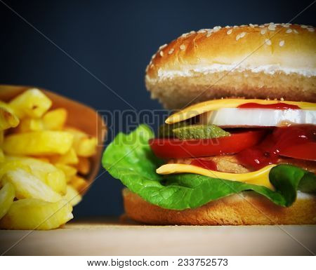 Close Up Of A Cheesburger With French Fries On A Wooden Table