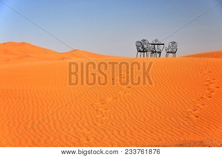 Metal Chairs And Tables Are Abandoned On The Sand Dune In The Sahara. Erg Chebbi, Morocco, Africa.