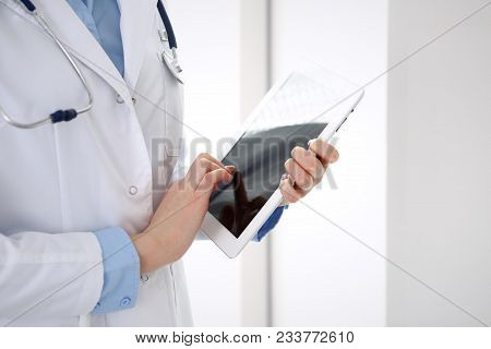 Woman Doctor Using Tablet Computer While Standing Straight In Hospital Closeup. Healthcare, Insuranc
