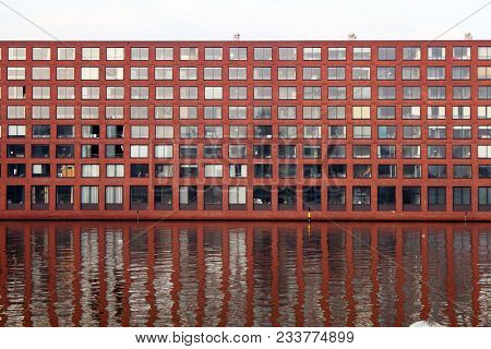 Red Brick Facade And Reflection In The Water Of A Building.