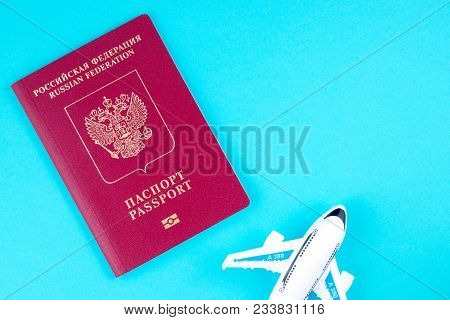 Plane And Red Russian Passport On Blue Background. Concept Of Traveling