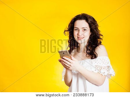 Woman In Summer Dress Holding Smartphone Over The Yellow Background
