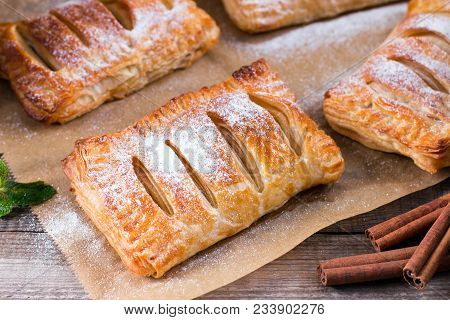 Puff Pastry With Apples And Powdered Sugar On A Wooden Table