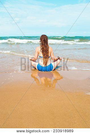 Young Woman Practicing Yoga By The Sea