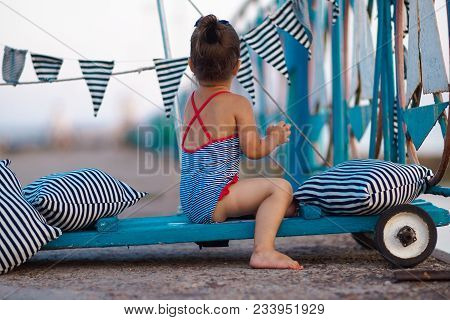 Little Girl In A Striped Swimsuit On The Pier With Dermatitis And Problem Skin On Her Hands