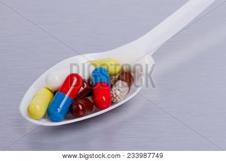 Capsules Of Medicine On White Spoon On Gray