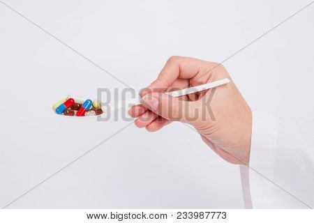 Doctor Holds Out Capsules On Spoon On White