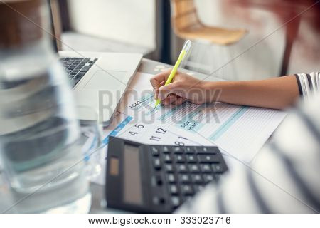 Close Up Of Entrepreneur Looking At Calendar And Filling Tax Declaration