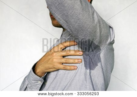 Man Perspiring Unpleasant Smell On A Blue Background. Wet Spot On My Blue Shirt From Sweat.