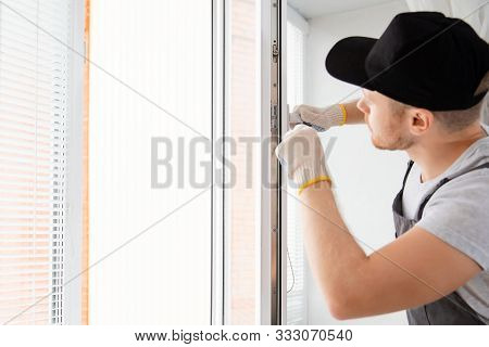 Construction Worker Man Uses Screwdriver To Screw Handle Install Plastic White Upvc Windows In House