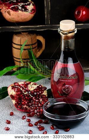 Narsharab. Glass Bottle And Saucer Of Pomegranate Sour Sauce With Fresh Ripe Pomegranate Fruits With
