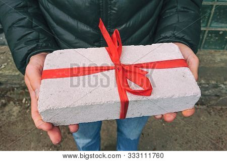 White Brick With Red Ribbon As Gift Box In Male Hands. Christmas Zero Waste Conccept