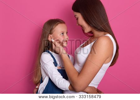 Mother And Daughter Look At Each Other While Posing Isolated Over Rosy Background. Attarctive Woman 