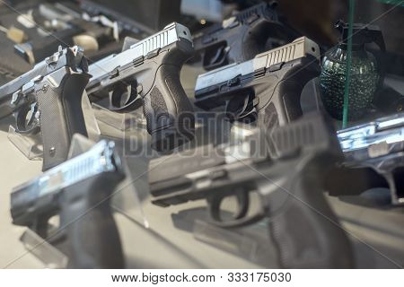 Black Pistols Behind The Glass Of A Weapon Store Counter. Unusual Look