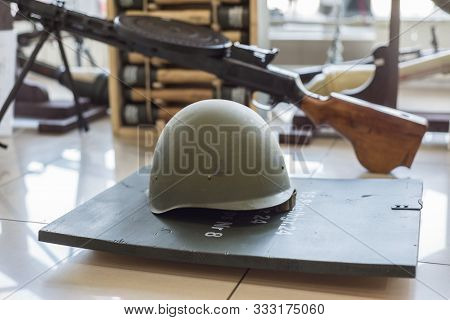 Green Military Helmets, Stand In The Arms Store On The Background Of Machine Guns And Machine Guns.