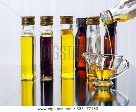 Vegetable Oil In Glass Transparent Bottles With Screw Caps. Bottles Of Vegetable Oil Reflected On Th