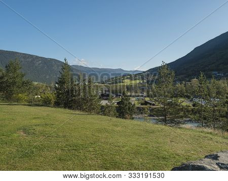 Lom, Norway, September 8, 2019: Vew On Houses Of Village Lom With Geen Grass, Hills And Rowan Tree. 