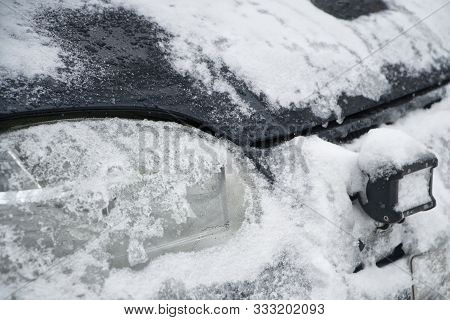 Snow-covered Headlights Of An Off-road Auto. Snowstorm And Road Safety In Winter Conditions. Dayligh