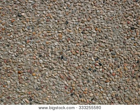 Concrete Wall With Sandy Shapeless Stones Inlaid Into It