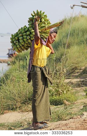 Monywa, Myanmar - February 14, 2019: Unidentified Man In Traditional Burmese Clothing Carries A Bran
