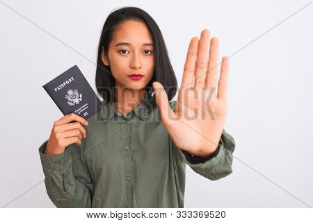 Beautiful chinese woman holding USA United States passport over isolated white background with open hand doing stop sign with serious and confident expression, defense gesture
