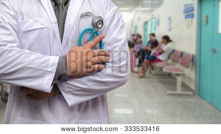 Doctor In Gown Uniform With Stethoscope Standing And Fold His Arms Over The Chest On Opd Background