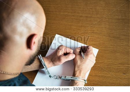 Men Hands With Handcuffs Fill The Police Record, Confession. On Top Of The Police Investigative Dete