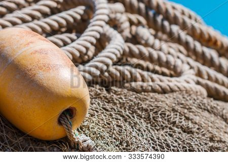 Old Fishing Nets With Weathered Buoy And Rope.