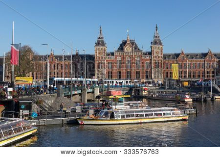 Amsterdam, Holland - October 30, 2019: Historical building of the Central Station at the Stationsplein near the Oudezijds Kolk water 