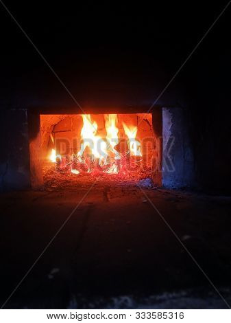 Bright Fire Burns In A Rustic Brick Stove On A Black Background