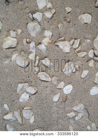 A lot of large white pebbles in porous gray concrete, texture