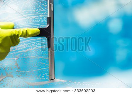 Cleaner Wearing Gloves Cleaning Soap Suds From Glass Window With Squeegee Wiper
