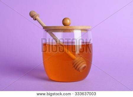 Jar Of Organic Honey And Dipper On Violet Background