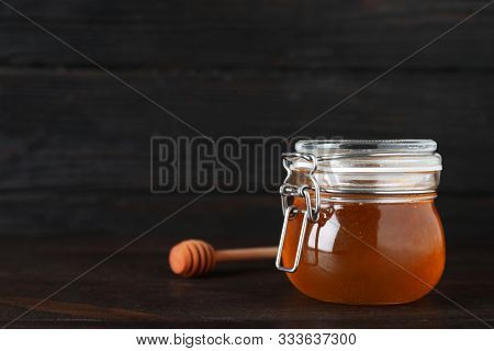 Jar Of Organic Honey On Wooden Table Against Dark Background. Space For Text