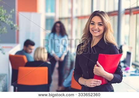 Business Woman With Folders Standing And Team Mates Working In Meeting Room At Office.