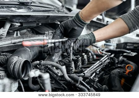 Close Up Of Mechanics Hands In Protective Black Gloves Using Wrench To Remove Spark Plugs For Repair